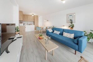 Ein modernes Wohnzimmer mit einem blauen Sofa, einem Couchtisch und einem Fernseher.