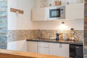 A modern kitchen with a microwave, coffee maker, and dishwasher. - La Rabine – Bel Appartement avec Terrasse Privée (Vannes)