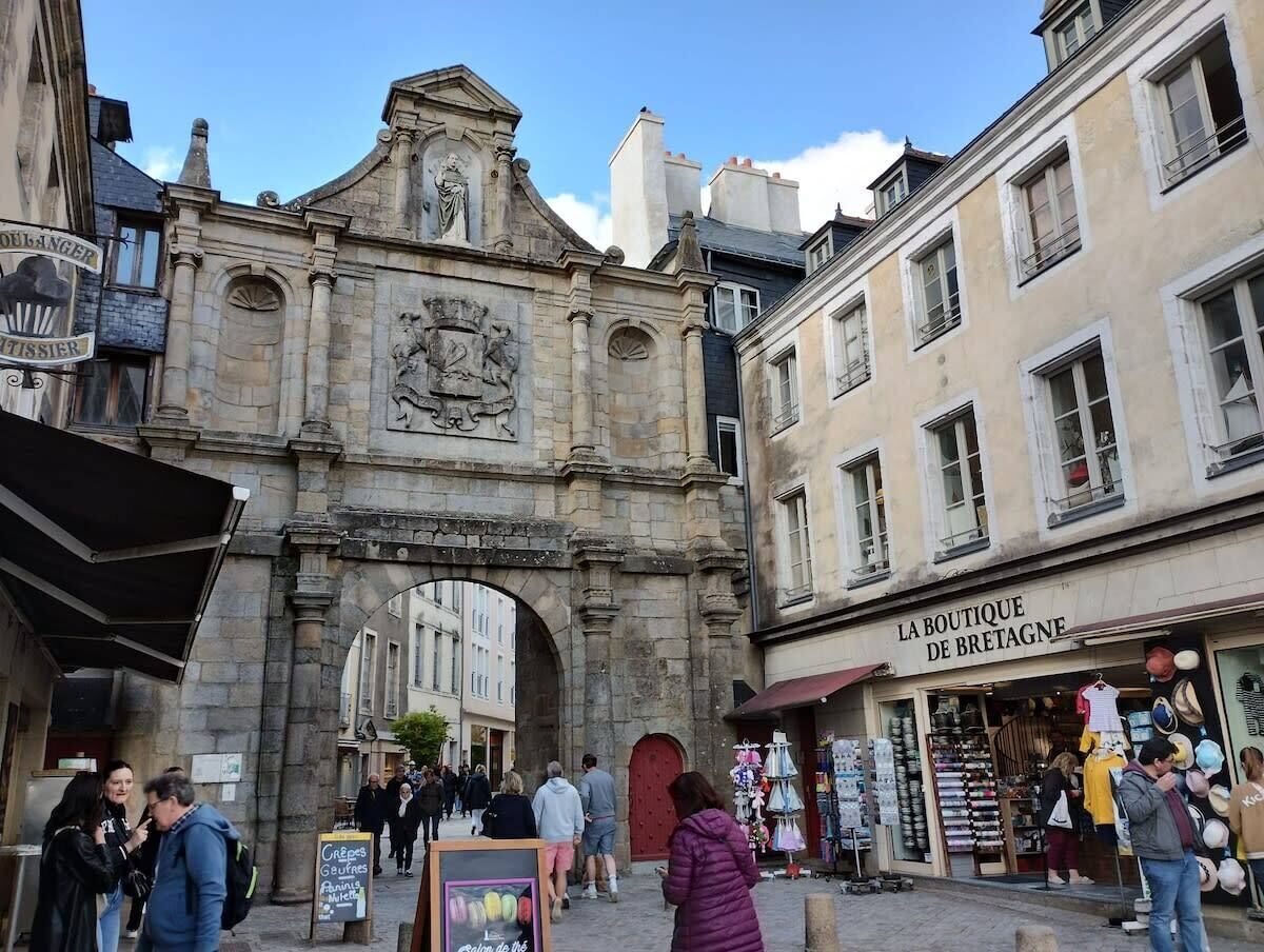 Un arco de piedra histórico con una tienda boutique llamada 'LA BOUTIQUE DE BRETAGNE' a la derecha.