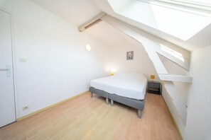 Ein Schlafzimmer mit Oberlicht, einem Bett, einem Nachttisch und einem Beistelltisch.