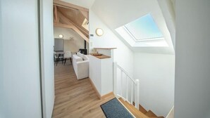 Un interior moderno con tragaluces, escalera de madera y un rincón de estar acogedor.
