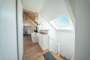 Ein modernes Interieur mit Oberlicht, einer Holztreppe und einer gemütlichen Sitzecke.