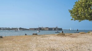 A sandy beach with boats in the water and a large building in the background. - Vue mer et garage privé • Port de Kernével (Larmor-Plage)
