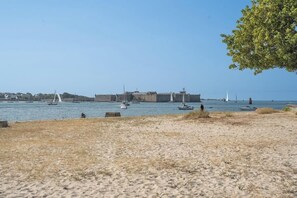 Ein Sandstrand mit Booten im Wasser und einem großen Gebäude im Hintergrund.