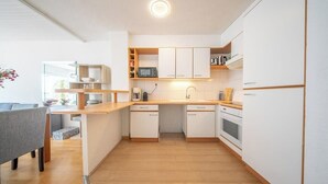 A modern kitchen with white cabinets, a wooden countertop, and a built-in microwave. - Vue mer et garage privé • Port de Kernével (Larmor-Plage)