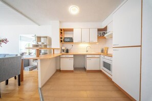 Eine moderne Küche mit weißen Schränken, einer Holz Arbeitsplatte und einer eingebauten Mikrowelle.