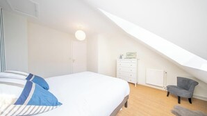 A bedroom with a bed, a dresser, a chair, and a radiator. - Vue mer et garage privé • Port de Kernével (Larmor-Plage)