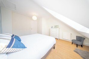 Ein Schlafzimmer mit einem Bett, einem Schminktisch, einem Sessel und einer Heizung.