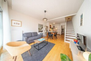 A modern living room with a sofa, coffee table, and a dining area with chairs. - Vue mer et garage privé • Port de Kernével (Larmor-Plage)