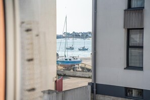 A view of a marina with boats docked, a building with a window, and a clear sky. - Vue mer et garage privé • Port de Kernével (Larmor-Plage)