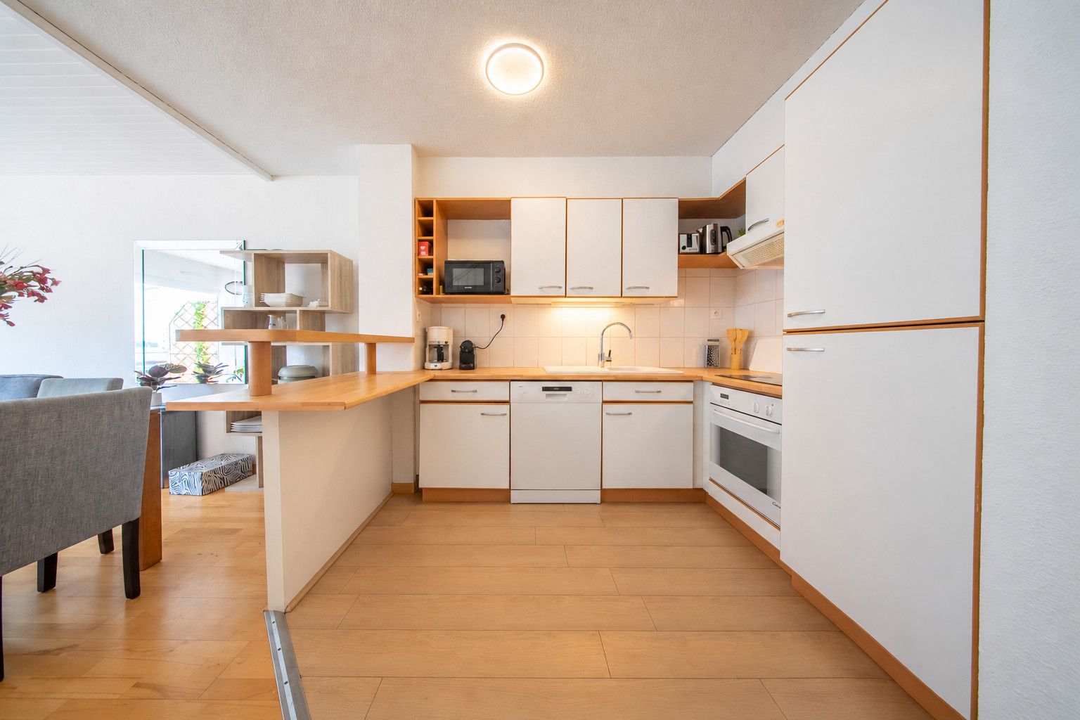 A modern kitchen with white cabinets, a wooden countertop, and a built-in microwave.