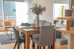 A dining area with a wooden table, grey chairs, a vase with flowers, and a view of the outdoors. - Vue mer et garage privé • Port de Kernével (Larmor-Plage)