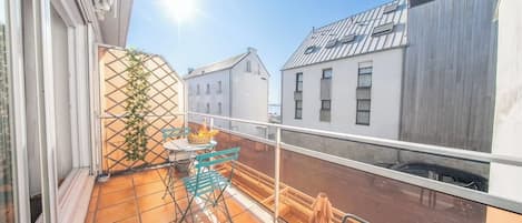 Ein Balkon mit Tisch, Stühlen, einer Topfpflanze und Blick auf benachbarte Gebäude.