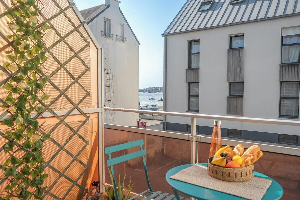 A balcony with a table, chairs, and a basket of fruit.