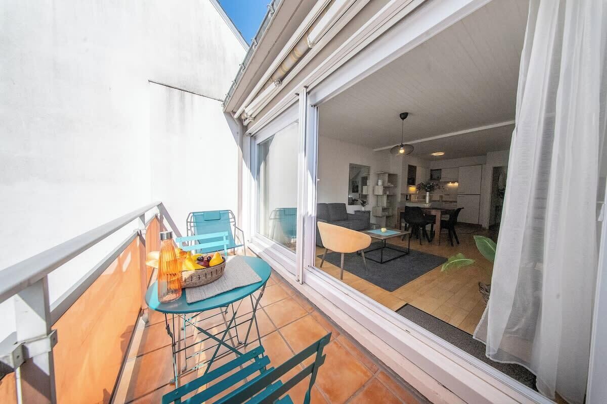 A balcony with a table and chairs, a sliding glass door leading to an interior dining area.