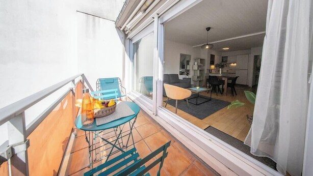 A balcony with a table and chairs, a sliding glass door leading to an interior dining area. - Vue mer et garage privé • Port de Kernével (Larmor-Plage)