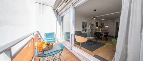 A balcony with a table and chairs, a sliding glass door leading to an interior dining area.