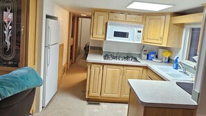 A compact kitchen with wooden cabinets, a refrigerator, a microwave, and a gas stove.