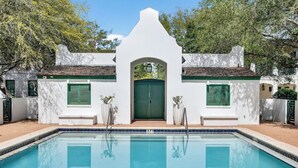 A swimming pool with a white building in the background. - Luxe Beach House: Steps to Rosemary, Beach, Pool & Bikes (Inlet Beach)