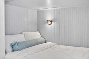 A bedroom with a bed, pillows, and a wall-mounted light fixture. - Luxe Beach House: Steps to Rosemary-Beach-Pool (Inlet Beach)
