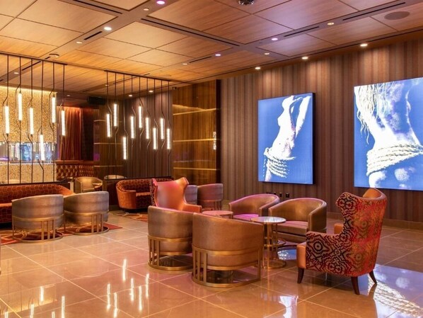 A modern lobby with a seating area, a large screen, and a wooden ceiling.