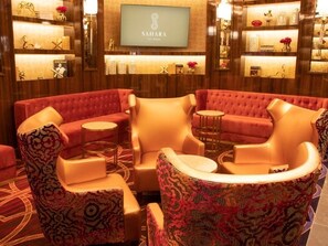 A hotel lobby with a red sofa set, a television mounted on the wall, and shelves with decorative items.