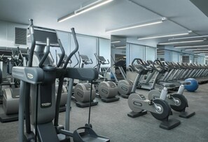 Een sportschool met meerdere loopbanden, elliptische trainers en krachttoestellen.