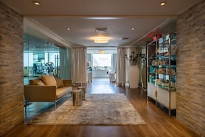 Een moderne hotellobby met een houten vloer, een bank, een bijzettafeltje en een glazen wand.