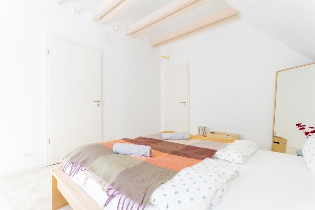 A bedroom with a bed, a bedside table, and a mirror.