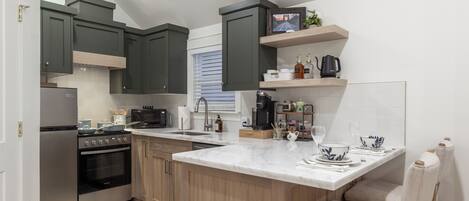 A modern kitchen with dark green cabinets, a central island, and a built-in oven.