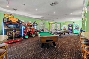 A room with arcade games, a pool table, and a green carpet. - Coconico Retreat At Windsor Palms (Kissimmee)