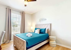Un lit bien fait, avec une couvre-lit bleue et des oreillers blancs, une lampe de chevet et un élément décoratif mural.