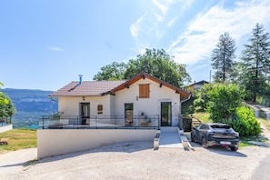A two-story house with a balcony, a car parked in front, and a scenic view of mountains and trees. - The Gîte De La Marquise (CONJUX)
