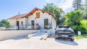 Une maison à deux étages avec une allée en gravier et une voiture garée.