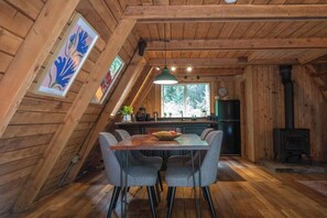 Ein Holzinnenraum mit Essbereich, Küche und Holzofen.