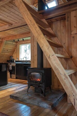 Ein Holzinnenraum mit Kamin, Küchenzeile und einem Fenster.