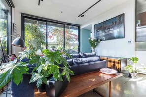 Ein modernes Wohnzimmer mit einer Couch, einem Couchtisch und großen Fenstern.