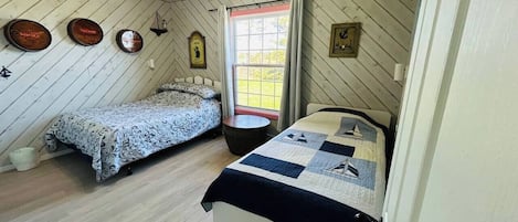 Une chambre avec deux lits, un ventilateur de plafond et une fenêtre avec des rideaux.