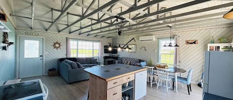 A spacious kitchen with a central island, a dining area with a table and chairs, a sofa, and a small kitchenette.