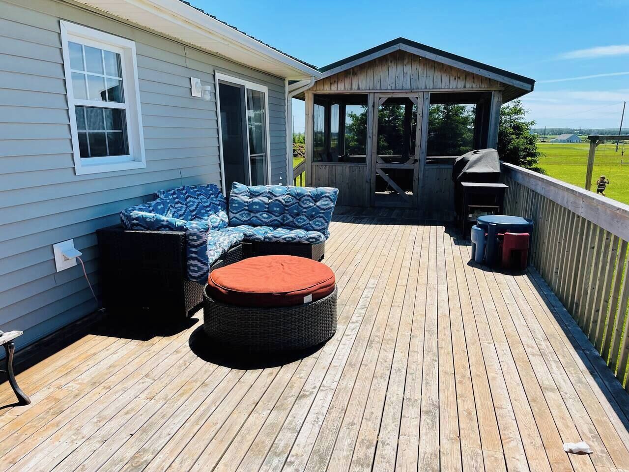 A wooden deck with outdoor furniture, a covered seating area, and a view of the surrounding landscape.