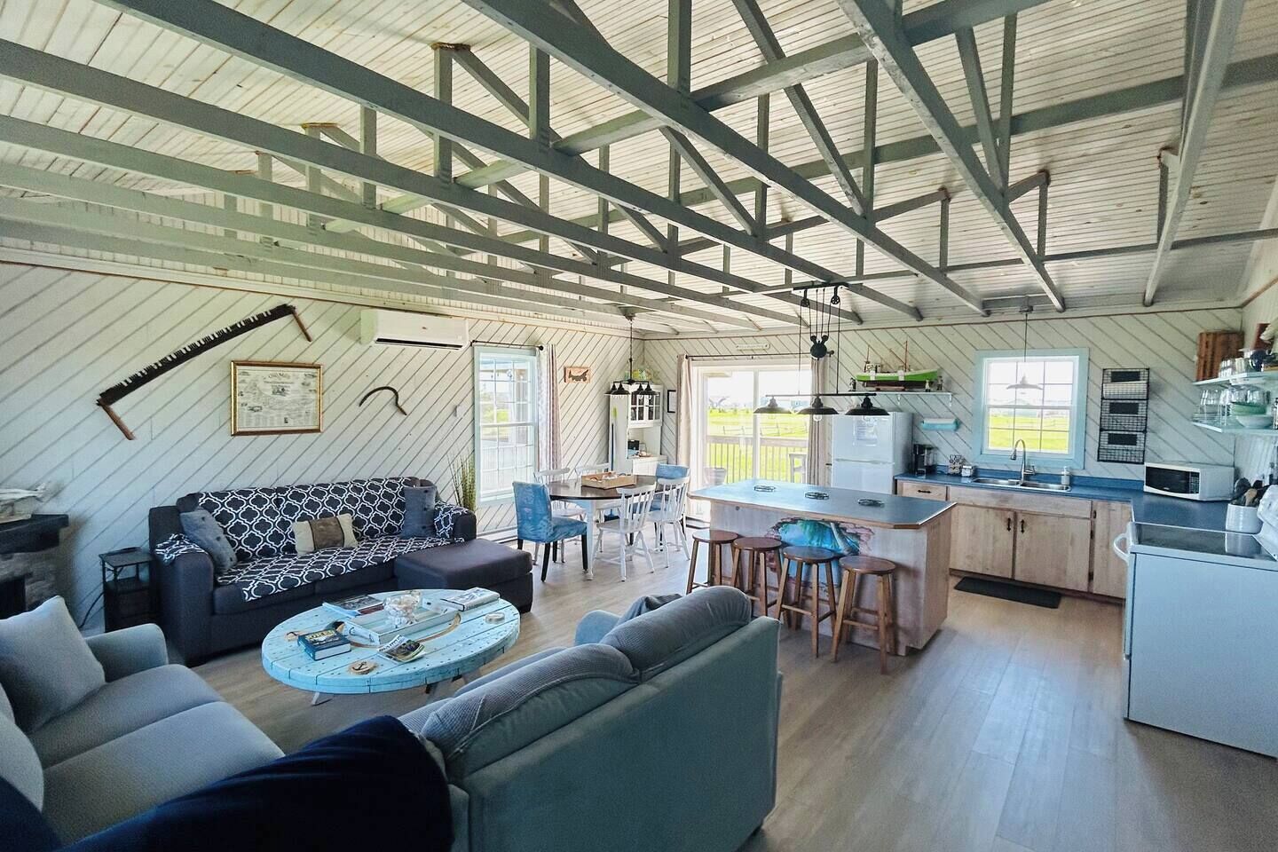 A spacious living area with a sofa, a coffee table, and a kitchen area with a bar stool.
