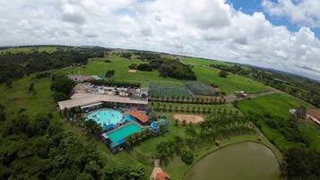 Vista aérea de um resort com piscina, escorrega aquático e um lago grande.