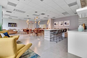 Um hall de hotel moderno com um bar central, área de estar e espaço para refeições.