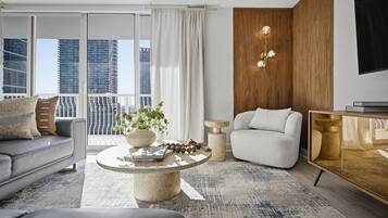 Una sala de estar moderna con un sofá, una mesa redonda de centro, una mesita auxiliar, una silla y un mueble para televisor.