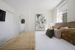 Habitación de hotel con una cama, un televisor de pantalla plana, un cuadro y una ventana con vistas.