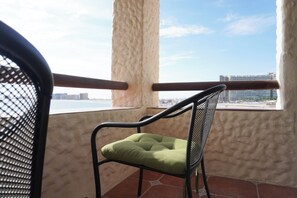 Una silla con cojín en un balcón con vista a un paisaje urbano y una masa de agua.