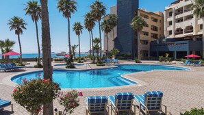 A pool area with lounge chairs, palm trees, and a view of the ocean. - Marina Pinacate B-302 (Puerto Peñasco)