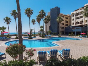 A pool area with lounge chairs, palm trees, and a view of the ocean. - Marina Pinacate B-302 (Puerto Peñasco)