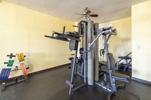 Un gimnasio con diverso equipo de ejercicio, incluyendo una máquina de pesas, mancuernas y un banco.