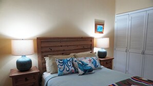 A bedroom with a wooden headboard, two bedside tables with lamps, a bed with a blue blanket and decorative pillows, and a wardrobe with louvered doors. - Marina Pinacate B-302 (Puerto Peñasco)